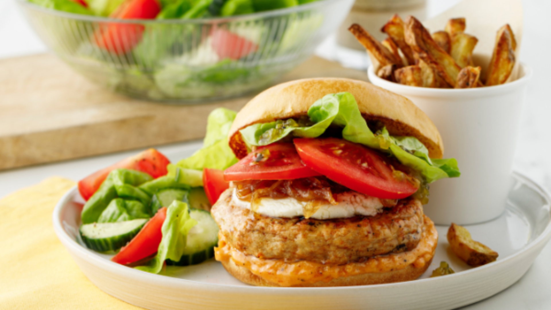 Image montrant un hamburger de poulet avec des tomates une salade et des frites